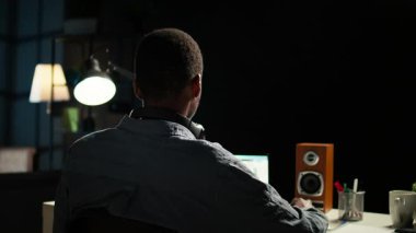 Afrikalı Amerikalı analist dans ederken, ritmi hissederken ve mali dengeyi kontrol ederken muhasebe analizi üzerinde çalışıyor. Uzaktan kumandalı işçi kulaklıkla en sevdiği harika müziği dinliyor. Kamera A.