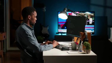 Genç programcı mühendis terminal penceresine ikili kod verileri yazıyor, ev düzeninde serbest çalışıyor. Yazılım geliştiricisi programlama dili ile sorun çözme üzerine çalışıyor. Kamera B.