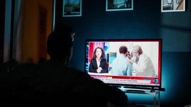 Kaygılı vatandaş TV 'de, kanepede haber spikerini dinleyip dünya çapında yaşanan son olayları anlatıyor. Genç yetişkin günlük medya manşetlerini takip ediyor. Kamera A.
