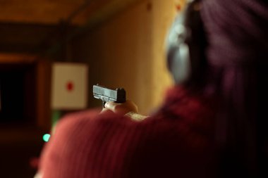 Atış poligonunda bir kadın ateşli silah kullanıyor, kağıt hedefleri kurşunla vuruyor. Kapalı alanda atış poligonu kuran, silahlarla eğlenen, boğa güreşçilerini vuran birini yakından çek.