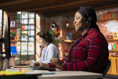 Neşeli çağrı merkezi operatörü mikrofonla konuşuyor, müşterilerin hesaplara ve cihazlara tekrar erişmelerine yardım ediyor. Neşeli müşteri merkezi çalışanı parolayı sıfırlamak için yardıma ihtiyacı olan müşterilere yardım ediyor