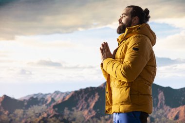 Genç kaşif dağın zirvesine ulaşıyor ve zirvede meditasyon yapıyor, sakin ve dikkatli bir şekilde zen meditasyonu yapıyor. Mutlu içerik arayıcısı kişisel bakım için doğayı seviyor.