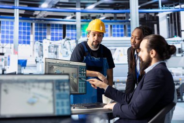 Fotovoltaik fabrikası yöneticisi güneş pillerinin enerji üretimini maksimuma çıkarmak için çalışanlar tarafından yapılan çalışmaları kontrol ediyor. Takım lideri teknisyenlerle işbirliği yapıyor, güneş paneli tesisinde sistem teftişi yapıyor.