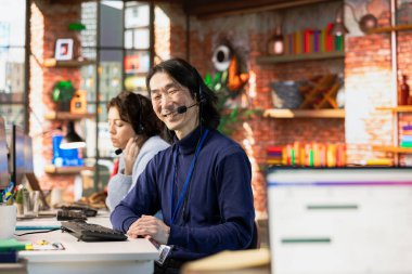 Neşeli Asyalı çağrı merkezi ajanının portresi müşteriyle konuşuyor, şirket iletişim kurallarına bağlı kalıyor. Müşteri ile sohbet sırasında neşeli deneyimli müşteri destek çalışanı çağrı metnini takip eder