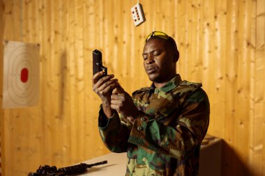 Ordu askeri atış menzilinde silah dolduruyor, hedefleri vurmaya hazırlanıyor, savaşa hazırlanıyor. Kapalı mekandaki askeri birlik, silah dolduruyor, koruyucu giysi giyiyor.