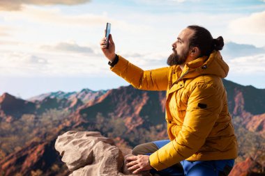 Yürüyüşçü maceracı dağın tepesindeki nefes kesici manzarayı yakalar, uzak bir dağ sırasına bakar ve vahşi doğanın güzelliğini kucaklar. Mucizeleri keşfetmenin sevinci.