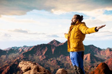 Genç kaşif dağın zirvesine ulaşıyor ve zirvede meditasyon yapıyor, sakin ve dikkatli bir şekilde zen meditasyonu yapıyor. Mutlu içerik arayıcısı kişisel bakım için doğayı seviyor.
