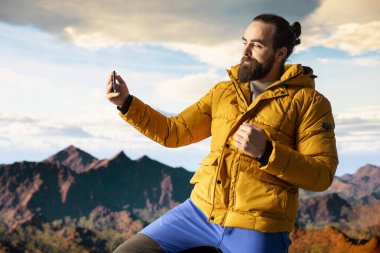 Doğa aşığı bir dağın tepesinde durup vahşi doğanın güzelliğini özümserken kendi fotoğraflarını çeker. Yüksek irtifa macerası dayanıklılığı ve kişisel gelişimi, fotoğrafçılığı sembolize eder.