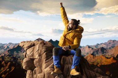 Tatmin olmuş maceracı, yüksek bir dağın tepesinde durur destansı manzarayı seyreder ve yürüyüş başarısıyla gurur duyar. Güçlü neşeli yürüyüşçü, tatminkar deneyimi hissediyor.