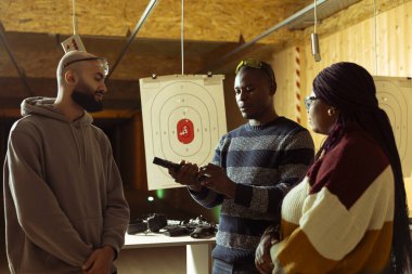 Atış poligonu güvenlik uzmanı müşterilerin güvenli bir şekilde silah kullanmalarını sağlıyor, silah taşıma görgü kurallarına uyuyorlar. Atış poligonu çalışanı müşterilerle kuralları tartışıyor