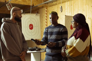 Atış poligonu güvenlik görevlisi müşterilere nasıl silah doldurulacağını gösteriyor. Menzil aktivitelerini denetliyor. Atış poligonu çalışanı düzgün silah kullanmayı öğretiyor.