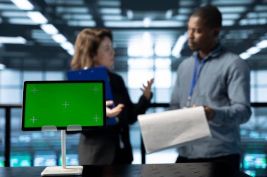 Veri merkezi müfettişinin önündeki maket tabletine odaklan. Müdürün yanındaki evrak dosyalarını incele. Sunucu çiftlik belgelerini denetleyen yöneticinin yanındaki izole ekran cihazını kapat