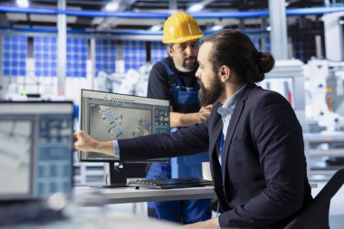 Fotovoltaik fabrikasındaki adam müdürle konuşuyor, arızalı sistemleri teşhis ediyor. Güneş panelleri imalat fabrikası mühendisi, kapatma süresini azaltmak için yöneticiden geri bildirim alıyor