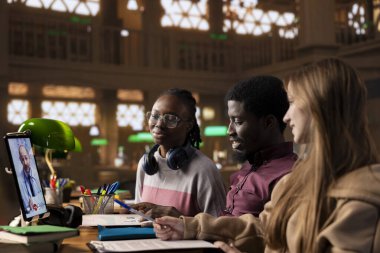 Doktorla telekonferansa katılan çok kültürlü bilim adamları bir kütüphane kampüsünde akademik tıp kursu için hastalıklar ve farmakoloji hakkında bilgi ediniyorlar. Stajyerlik..