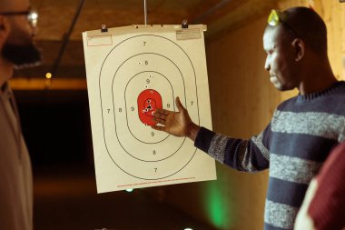 Galeri çalışanı öğrencilere tabancalarla nasıl hedef alınacağını öğretiyor. Atış menzili uzmanı, hedeflere ateş ederken yüksek seviyede silah kullanma becerisi kazandırıyor.