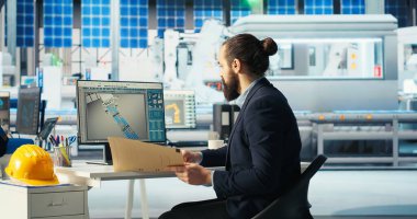 Fotovoltaik fabrikası mühendisi kahve içiyor sistem parametrelerini ayarlıyor. Teknisyen sıcak içeceğin keyfini çıkarıyor ve güneş paneli üretim tesisinde enerji arzını optimize ediyor.