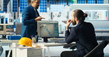 Fotovoltaik fabrikasındaki mühendis iş arkadaşıyla konuşuyor, arızalı sistemleri teşhis ediyor. Güneş panelleri fabrika iş arkadaşlarını üretiyor. Kesintileri azaltmak için beyin fırtınası yapıyorlar.