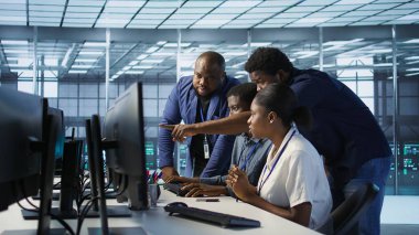 Ekip mühendisleri sunucu odasında konuşuyor, felaket kurtarma planları geliştiriyor ve en az dinlenme süresini sağlıyor. Veri merkezi çalışanlarından oluşan bir ekip beyin fırtınası yapıyor, performansı izliyor, kamera A