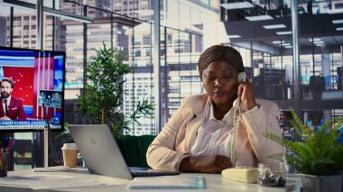 Genel müdür ofisteki sabit telefondan sekreterini arıyor. Geliştirme ile ilgili önemli işleri halletmek için gerekli evrakları soruyor. Afrika kökenli Amerikalı patron görev yönetimi yapıyor. Kamera B.