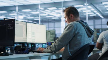 Monitördeki verileri analiz ederken kas kramplarını azaltmak için sunucu odasında esneme hareketleri yapmaktan yorgun düşmüş. Veri merkezinde yorgun bir adam çok çalıştıktan sonra vücudu rahatlatıyor, kamera A