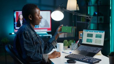 Yeşil ekran akıllı telefonundaki videoları izlemek için borsayı kontrol etmeye ara veren bir kadın. Krom anahtar telefon kullanarak evden çalışan hissedar pazar payı artışına bakıyor