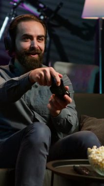 Dikey video, oyun konsolunda oynarken tüm düşmanları yendikten sonra böbürlenen oyun kurucunun gururu. Memnun oyuncu, video oyunu kazandıktan sonra kendini tebrik ediyor. Kamera A 'yı kullanıyor.