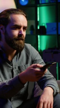 Dikey video, TV 'nin önündeki koltukta oturan, abonelik temelli yayın yapan, uzaktan kumandayla gezinen sıkıcı kişi. Yorgun adam TV 'de VOD programları seyrediyor.