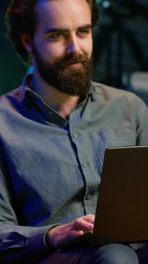 Dikey Videocu TV 'de şok edici bir son dakika haberi izlerken neon ışıklı dairede dizüstü bilgisayar kullanıyor. Televizyonun sesini açan kişi, dizüstü bilgisayar ve kamera kullanarak kanepede otururken yaşanan olaylara şaşırdı.