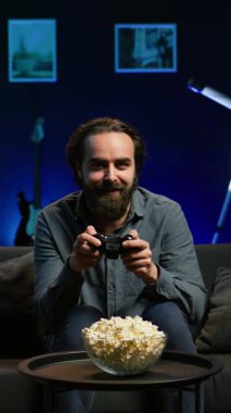 Neon ışıklı bir dairede video oyunu oynayan heyecanlı bir adam elinde kontrolör tutuyor. Konsol sistemindeki PVP oyununa katılmak için joystick kullanan mutlu oyuncu, rahatlıyor ve