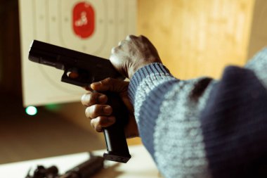 Atış poligonu kurma, ateş etme mekanizması kurma konusunda uzmandır. Kapatın. Afrika kökenli bir Amerikalı antrenman sırasında çekiç çekip ateş etmeye hazırlanıyor.