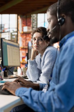 İşbirliği yapan çağrı merkezi ajanlarını ara. Bilgisayardaki hesap tablosundaki müşteri etkileşimlerini kaydet. Müşteri hizmetleri temsilcisi ve Afro-Amerikan iş arkadaşı müşteri yönetimi yazılımı kullanıyor.