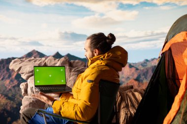 Kararlı dağcı, kişisel gelişimin yürüyüş yolculuğundan esinlenerek yeşil ekranın yanındaki dağ zirvelerinin keyfini çıkarıyor. Erkek yürüyüşçülerin macerası ve açık havanın güzelliği.