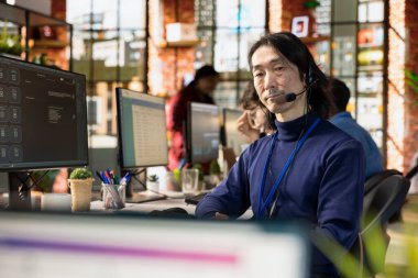 Kulaklık takan kıdemli çağrı merkezi ajanının portresi müşterilerin sorunlarını çözüyor, mikrofona konuşuyor. Kulaklık kullanan deneyimli Asyalı müşteri hizmetleri çalışanı.