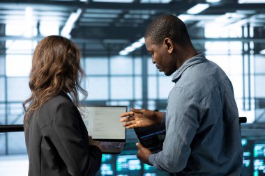 Veri merkezi işyerindeki programcılar süper bilgisayarların enerji kullanımını ayarlamak için dizüstü bilgisayar kullanıyorlar. Sunucu odası IT personeli kodları defterde, ekipman teçhizatlarının bakımını yapıyor.