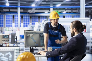 Güneş panelleri bitki yöneticisi, analiz verilerine dayanarak stajyere verimliliği nasıl optimize edeceğini öğretiyor. Fotovoltaik fabrikası ekip lideri yenilikçi güneş hücreleri dizaynı üzerinde çalışan yeni bir çalışana rehberlik ediyor.