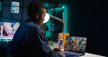 İş görüşmesi sırasında apartman ofisindeki video görüşmesinde uzaktan çalışan meslektaşlarını selamlıyor. Uzak video konferansına katılan serbest meslek sahibi bir kadın evde kamera B iken tele-iş görüşmesine katılıyor