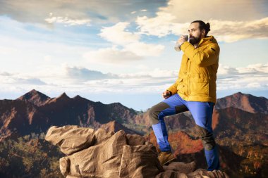 Doğa aşığı dağ sırasına tırmanıyor ve susuzluk için duruyor, manzaraya ve vahşi doğaya hayran kalıyor. Genç kaşif su içiyor ve su şişesini su içmek için kullanıyor..