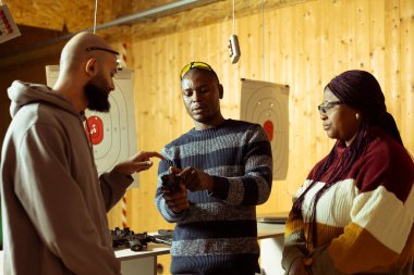 Galeri çalışanını vurmak öğrencilere ateş etmeden önce horoz tabancası kullanmayı öğretmek. Afrika kökenli Amerikan atış poligonu eğitmeni, silah konusunda yüksek seviyede uzmanlaşmak için rehberlik ediyor.
