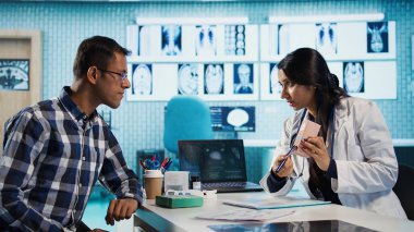 Kadın uzman cildini ultraviyole ışınlara karşı korumak için güneş kremi ve nemlendirici sürmesini tavsiye ediyor. Dermatoloji uzmanı cilt bakımı yapan hastalara yardım ediyor. Kamera B.