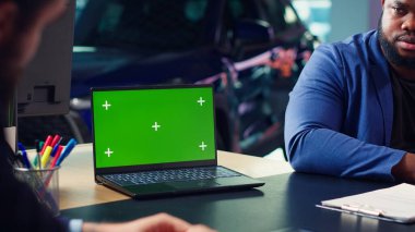 Satış elemanı müşterilerine araba kabul seçenekleri sunmak için izole ekran bilgisayarı kullanıyor, satın almak için onları etkilemeye çalışıyor. Showroom temsilcisi müşterilere garanti veriyor, kroma anahtar defteri, kamera A