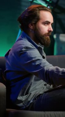 Dikey Videocu dizüstü bilgisayarda çalışırken dikkat dağıtmak için televizyon kanalını seçerken apartman dairesindeki kanepeye uzandı. Uzaktan çalışan, dizüstü bilgisayarda şirket görevlerini çözen, içinde TV şovu olan.