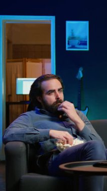 Kanepede oturup stresten patlamış mısır yiyen dikey videolu üzgün adam canlı yayında acıklı bir dram filmi izliyor. İnsan yiyen, TV 'den rahatsız olan favori karakter ölüyor, kamera