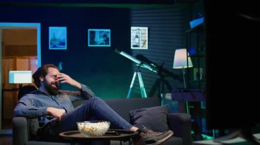 Komik komedi filmi izlerken koltukta oturup gülen, patlamış mısır yiyen eğlenceli bir adam. Apartmandaki neşeli insan abur cubur yiyor ve film sahnesinde komik bir şakayla eğleniyor, kamera B