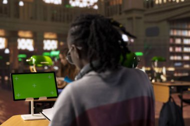 Genç öğrenci sınav hazırlıkları için araştırma yaparken, güvenilir akademik kaynaklardan eğitim bilgileri okurken, modelleme sergisi kullanır. Öğrenci notlarını ders kitabında tamamlar..