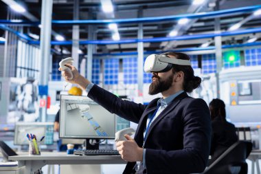 Fotovoltaik fabrika mühendisi VR teçhizatını kullanarak robot makineleri test ediyor. Güneş panelleri imalat parametrelerine danışmak için sanal gerçeklik teknolojisi kullanan bitki uzmanı, ayarlamalar yapıyor