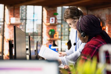 Çağrı merkezi güvertedeki uzman bilgisayardaki çalışanlarla birlikte evrak dosyalarını inceliyor. Müşteri destek müdürü, iş ile uyumlu stajyer şirket belgelerini açıklıyor