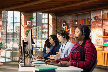 Çok ırklı çağrı merkezi çalışanlarından oluşan bir ekip bilgisayar klavyesinde yazarak müşterilere dijital iletişim kanallarından yardım ediyor. Müşterilerle canlı sohbette çok ırklı müşteri desteği