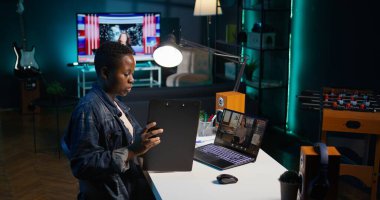 Çeşitli şirketler için çalışan Afrikalı Amerikalı tele-işçi Asyalı yöneticiyle iş görüşmesi videosu görüşmeleri yapıyor. Uzaktan çalışan yönetici ile video konferansında konuşuyor, grafikler sunuyor, kamera B