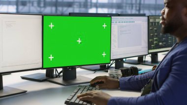 Sunucu odasında yeşil ekran bilgisayar kullanan bir mühendis en az arayı sağlayacak felaket kurtarma planları geliştiriyor. Veri merkezi çalışanı Model PC 'ye bakıyor, performansı izliyor, kamera A