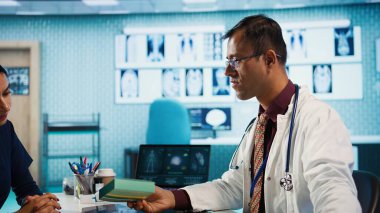 Genel pratisyen hekim, sağlık sigortasına vitamin ve ağrı kesici öneriyor. Talimatları ve doğru dozda ilaç içeren reçeteli bir belge yazıyor. Kamera B.